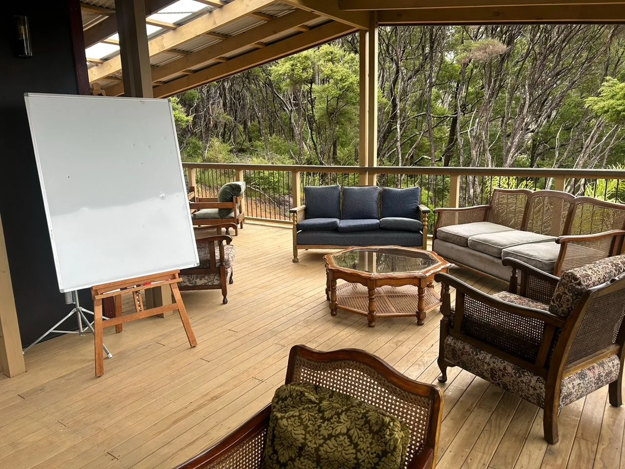 Outdoor boardroom deck at Mason Canyon — whiteboard, breakout seating, native bush views, Great Barrier Island